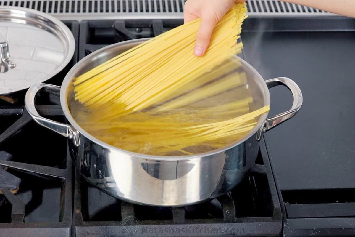 Chicken Tetrazzini is a cheesy, creamy chicken pasta bake that will have your family refilling their bowls! Make this easy casserole today! Spaghetti pasta going into a pot of boiling water on the stove