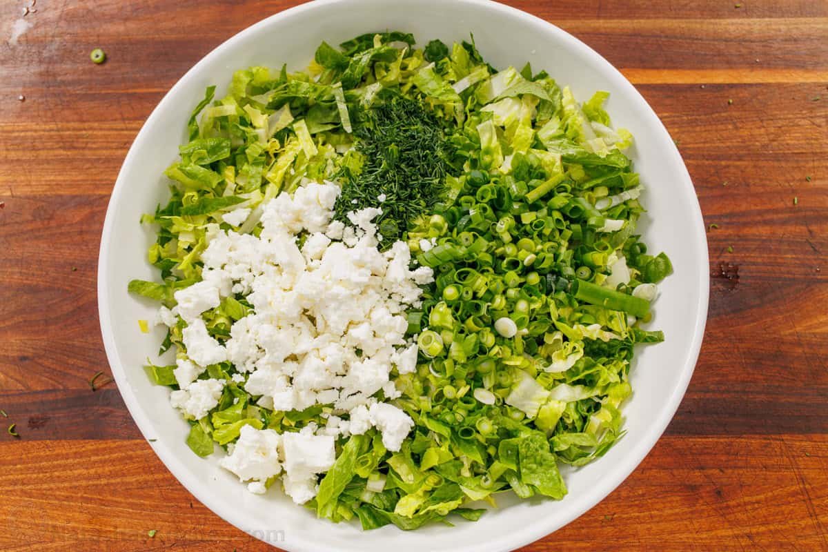 This easy traditional Maroulosalata recipe had crispy lettuce, feta cheese, and fresh herbs for a go-to Greek Lettuce Salad recipe! How to mix salad greens in a bowl including romaine lettuce, feta, dill, and green onions