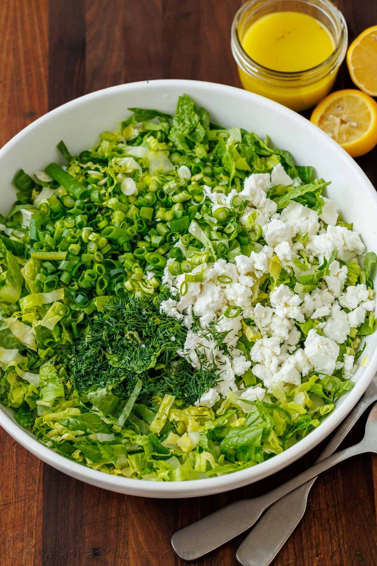 This easy traditional Maroulosalata recipe had crispy lettuce, feta cheese, and fresh herbs for a go-to Greek Lettuce Salad recipe! Maroulosalata Green lettuce salad prepped ahead to store in a white bowl with salad dressing on the side