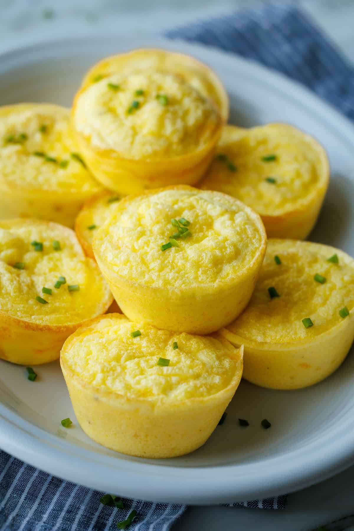 My Cottage cheese egg bites are as good as Starbucks egg bites recipe, but with less hassle! Choose your favorite mix-ins to make them yours. Breakfast muffins on a serving platter with a blue napkin