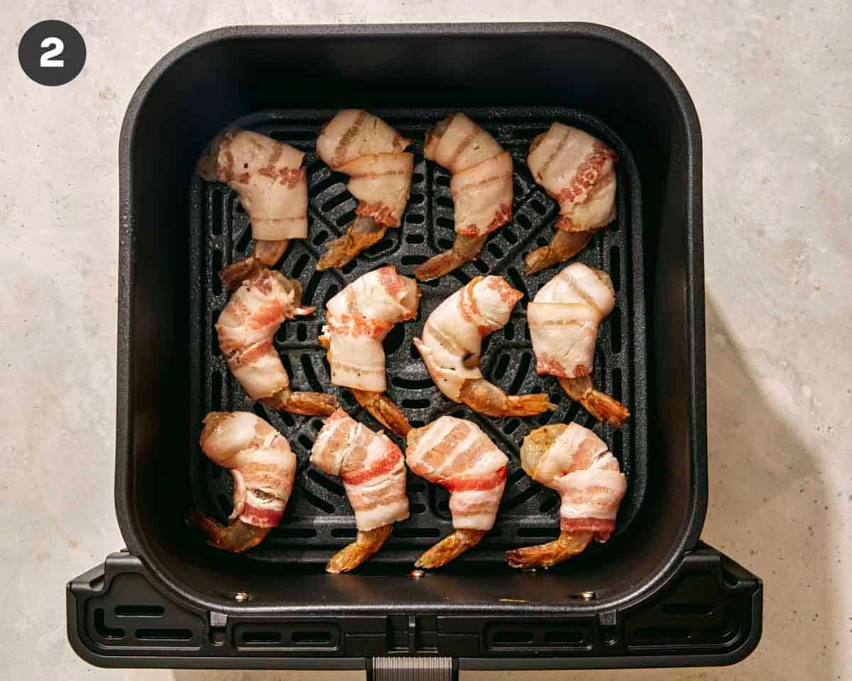 Shrimp wrapped in bacon and in an air fryer ready to be cooked.