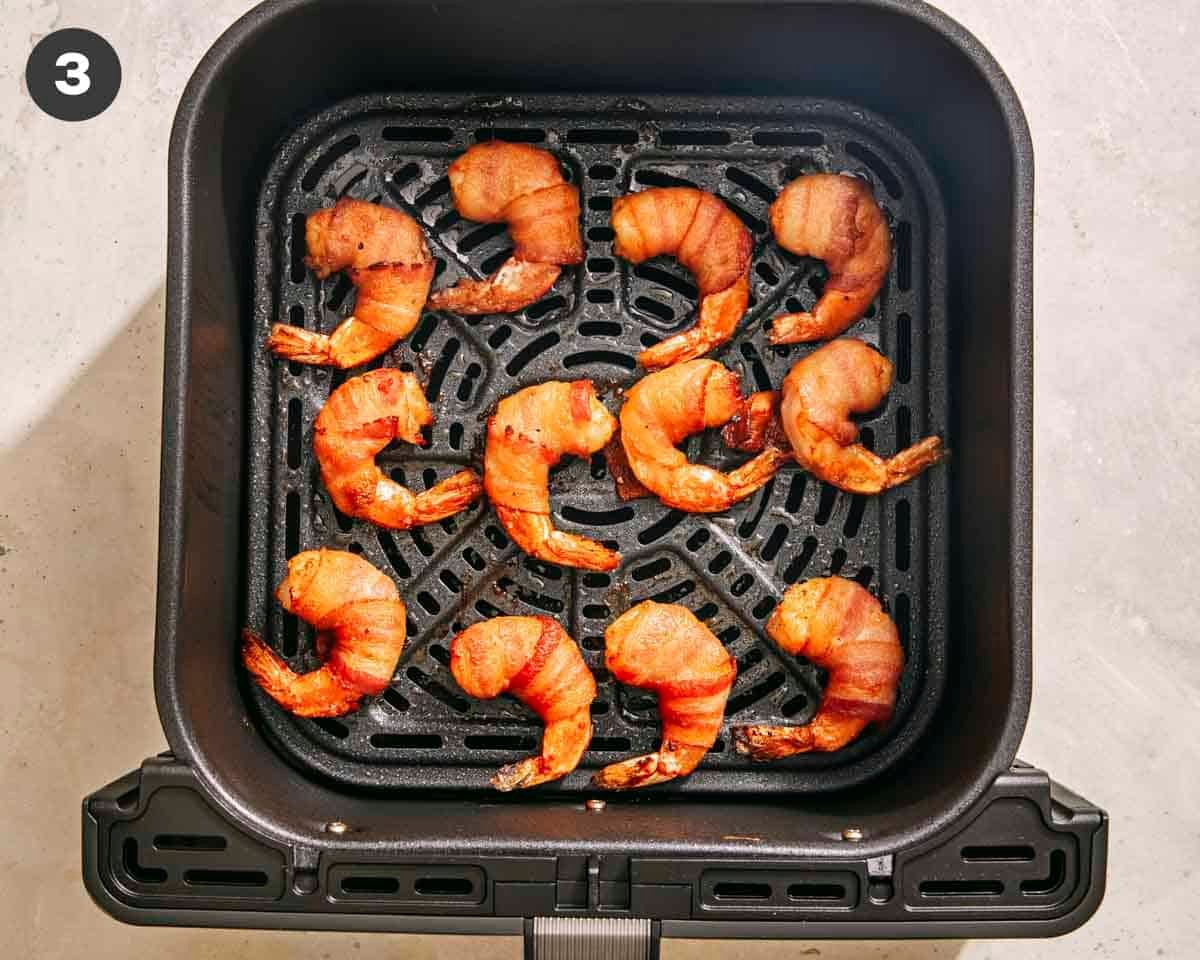 Air fryer shrimp wrapped in bacon cooked in an air fryer basket.