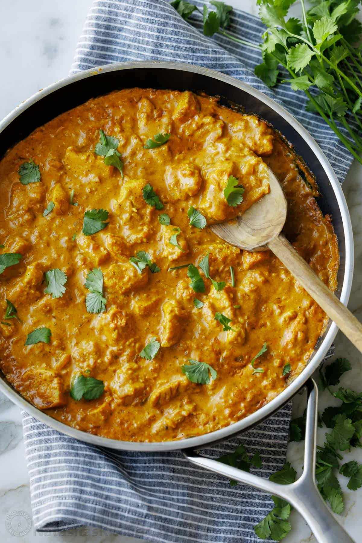 Chicken Korma is rich, creamy, and full of warm spices. This easy yet impressive dish brings the flavors of India to your kitchen. Serve over rice and enjoy! Chicken Korma in a large skillet garnished with chopped cilantro. One-inch pieces of chicken in a beautiful curry sauce.