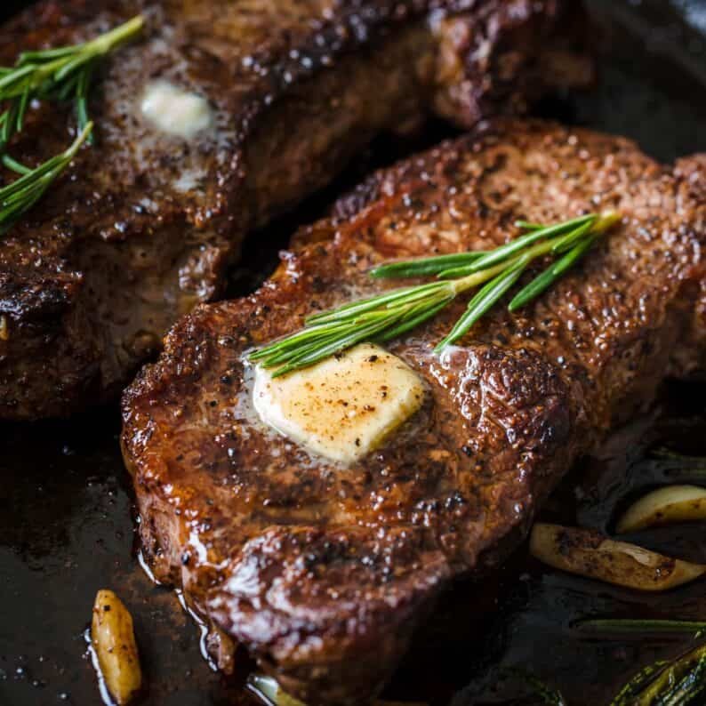 Pan-Seared Steak on skillet topped with butter and fresh rosemary