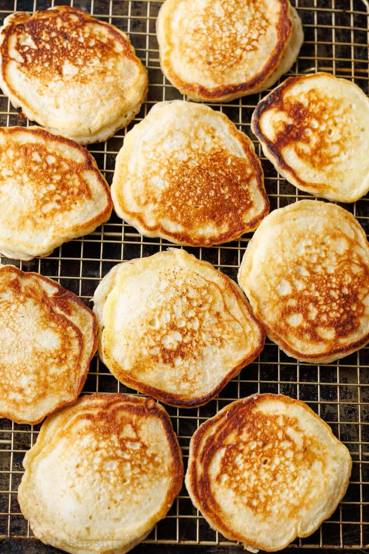 Overnight Sourdough Pancakes are easy! Mix everything before bed, leave at room temp overnight, and wake up to bubbly, ready-to-cook pancake batter. Sourdough Pancakes on a wire rack to cool.