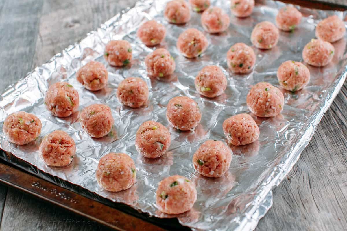30-minute Turkey Teriyaki Meatballs are just as juicy with less guilt! Simply bake the meatballs and cover them with homemade teriyaki glaze. Homemade meatballs on a baking sheet lined with foil