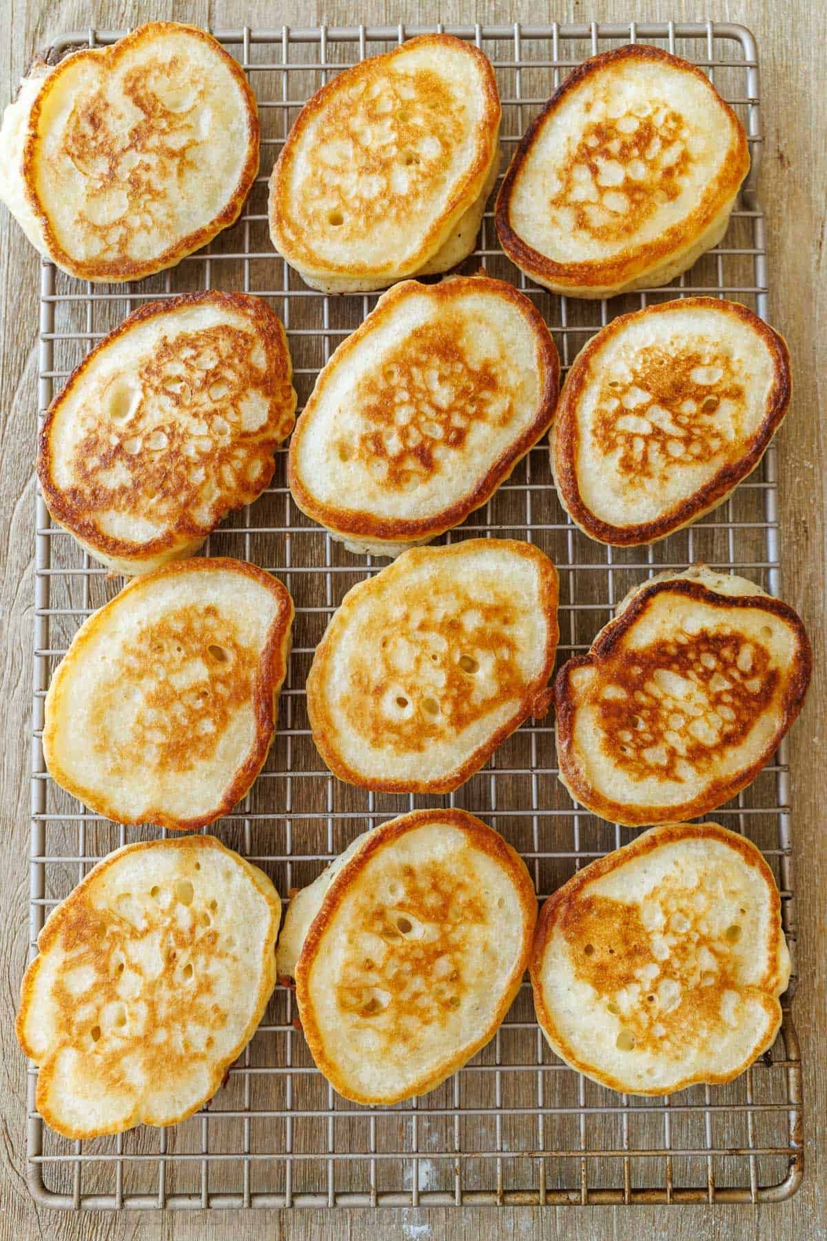 Sourdough Discard Pancakes are a delightful twist on the classic breakfast favorite, with a soft and spongy texture infused with tangy flavor from sourdough starter. They're a satisfying treat! Sourdough discard pancakes lined on a cooling rack, with crispy golden edges.