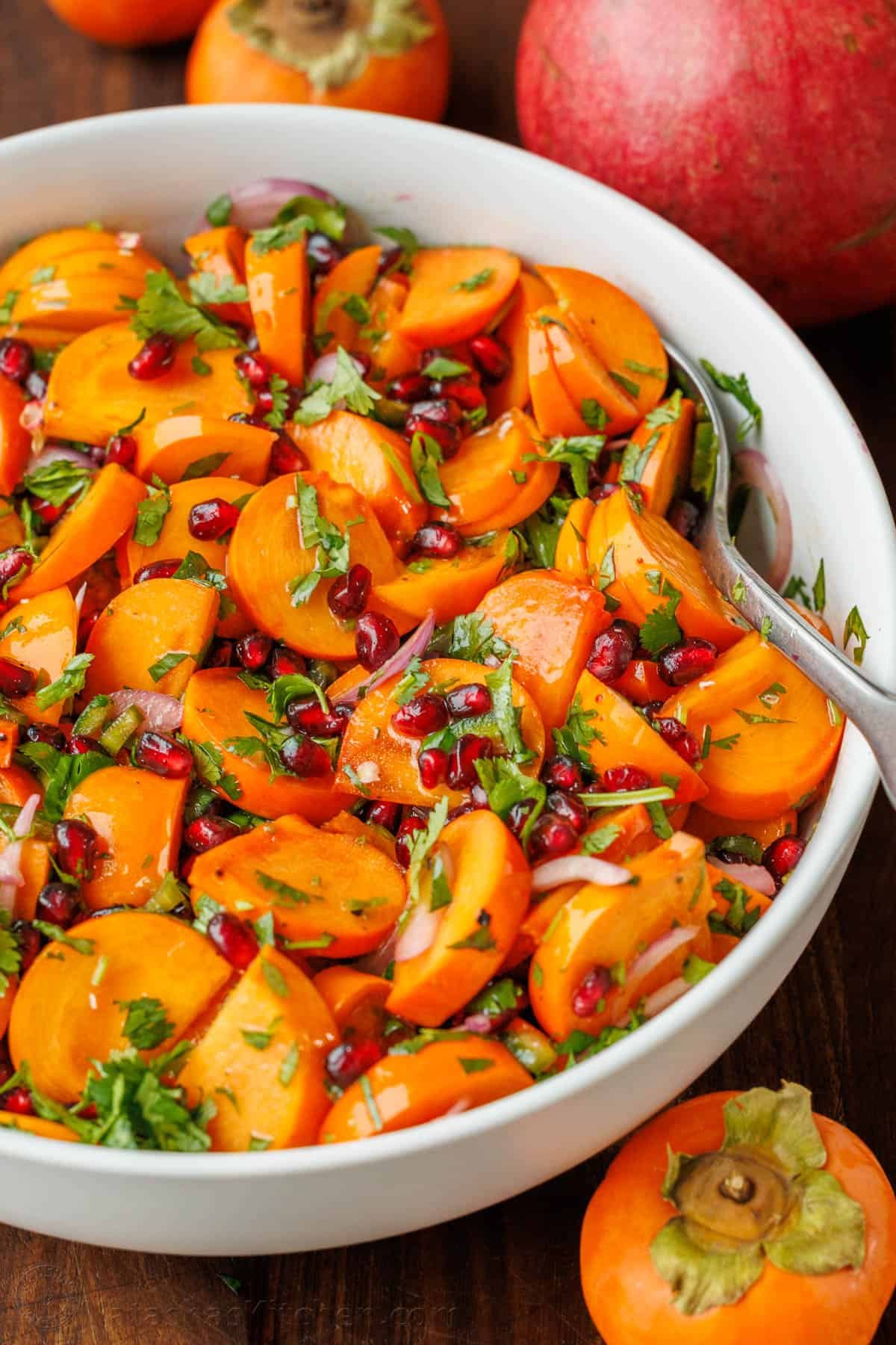 This easy persimmon pomegranate salad with lime cilantro dressing is one of the most exciting salads I've tried. It's vibrant and memorable! Easy Persimmon Pomegranate Salad in a white bowl with cilantro garnish