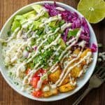 Easy Fish Taco Bowl recipe using seasoned fish chunks, Cilantro Lime Rice, Crema Sauce, and taco toppings