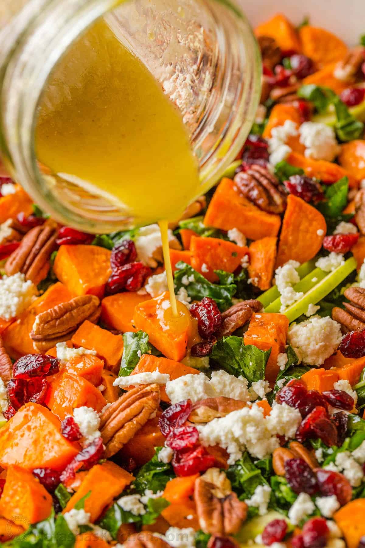 Roasted Sweet Potato Salad has all the best Fall flavors. Loaded with kale, sweet potato, apple, pecans, goat cheese, and the best dressing. Pouring maple vinaigrette dressing over sweet potato salad
