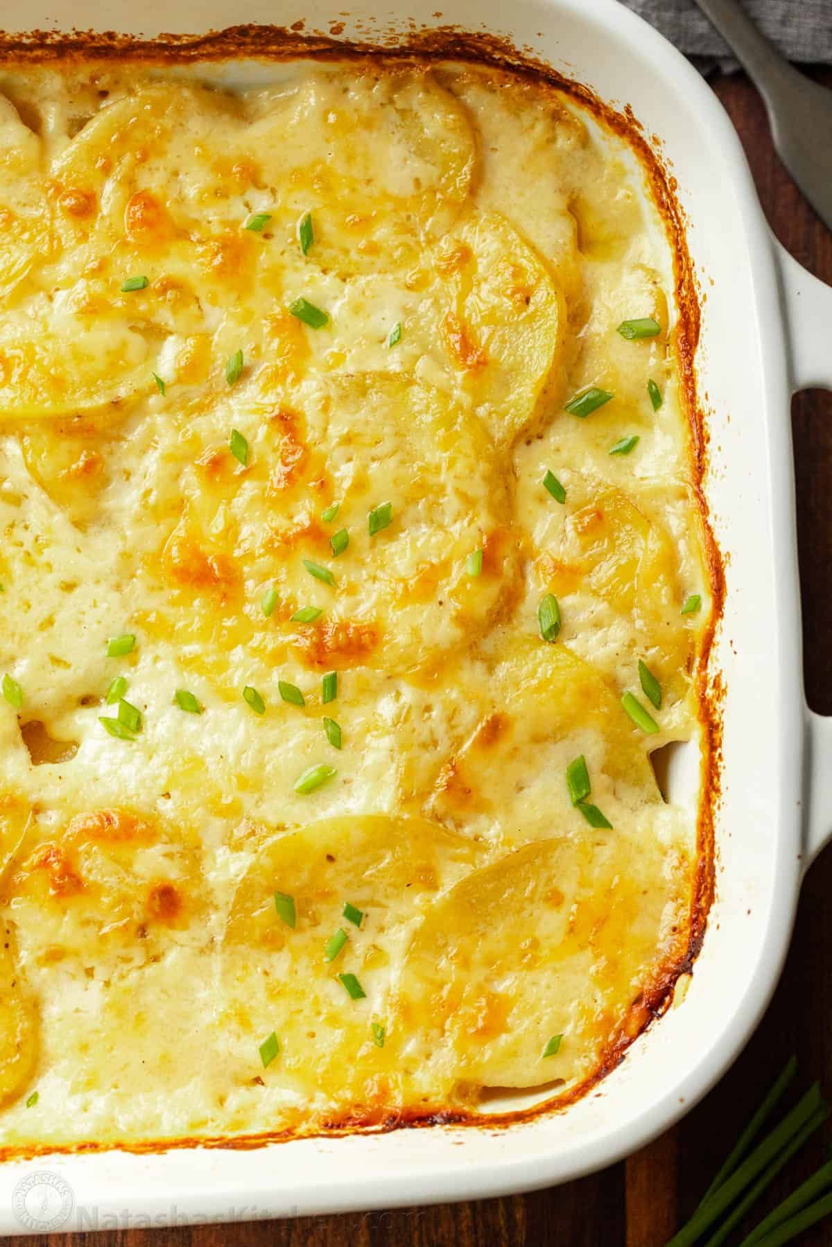 Creamy Au Gratin Potatoes are made with thinly sliced potatoes baked in a rich cheese sauce. Potato Gratin is an impressive holiday side dish. Golden baked au gratin potatoes in a baking dish.