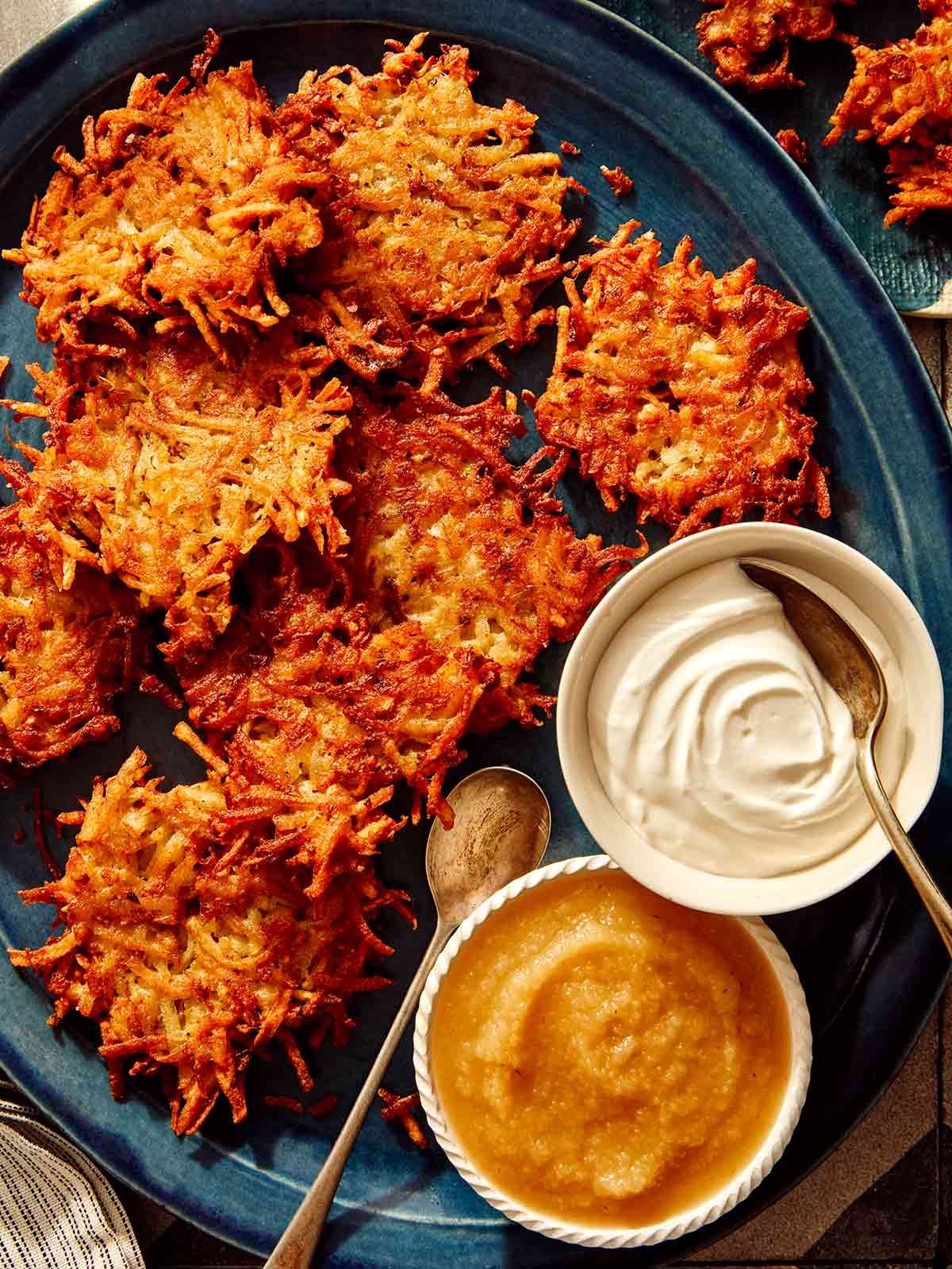 Potato latkes on a platter with plates to serve next to it.