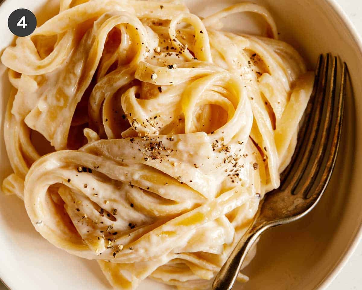 A close up of one pot fettuccine alfredo with cracked black pepper and a fork.