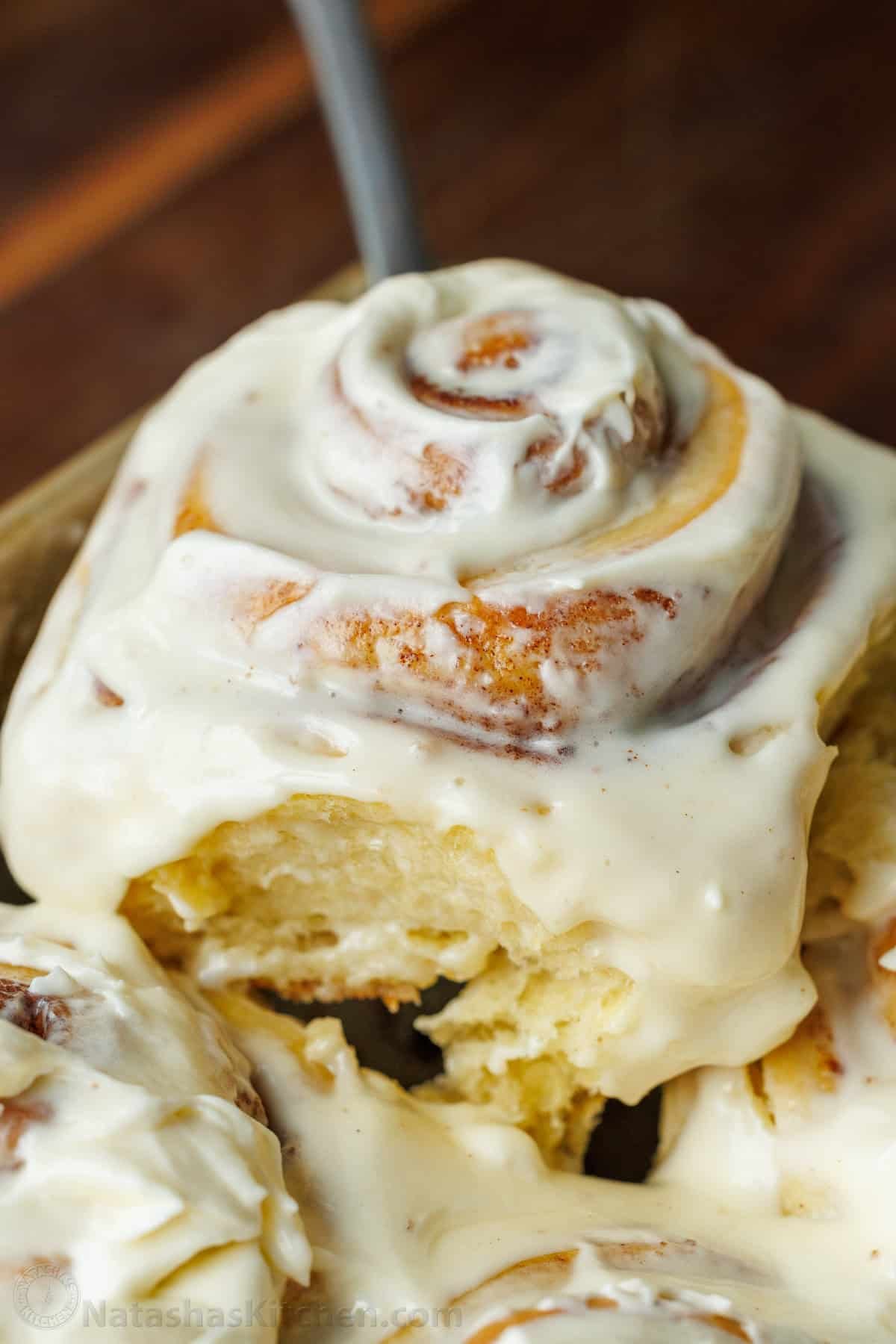 The perfect recipe for soft, fluffy, and buttery Sourdough Cinnamon Rolls, layered with cinnamon sugar and topped with creamy cream cheese frosting. A closeup of a cinnamon roll showcasing the moist dough, covered in cinnamon and smothered in cream cheese frosting.