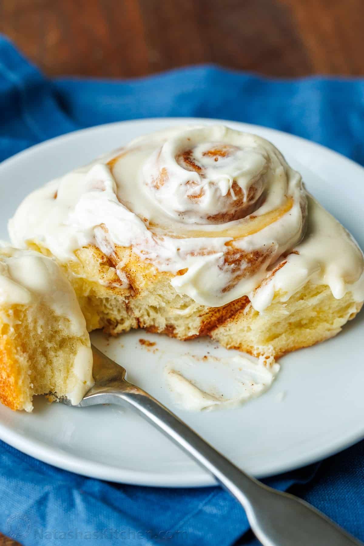 The perfect recipe for soft, fluffy, and buttery Sourdough Cinnamon Rolls, layered with cinnamon sugar and topped with creamy cream cheese frosting. A Sourdough Cinnamon Roll with a fork on a plate.