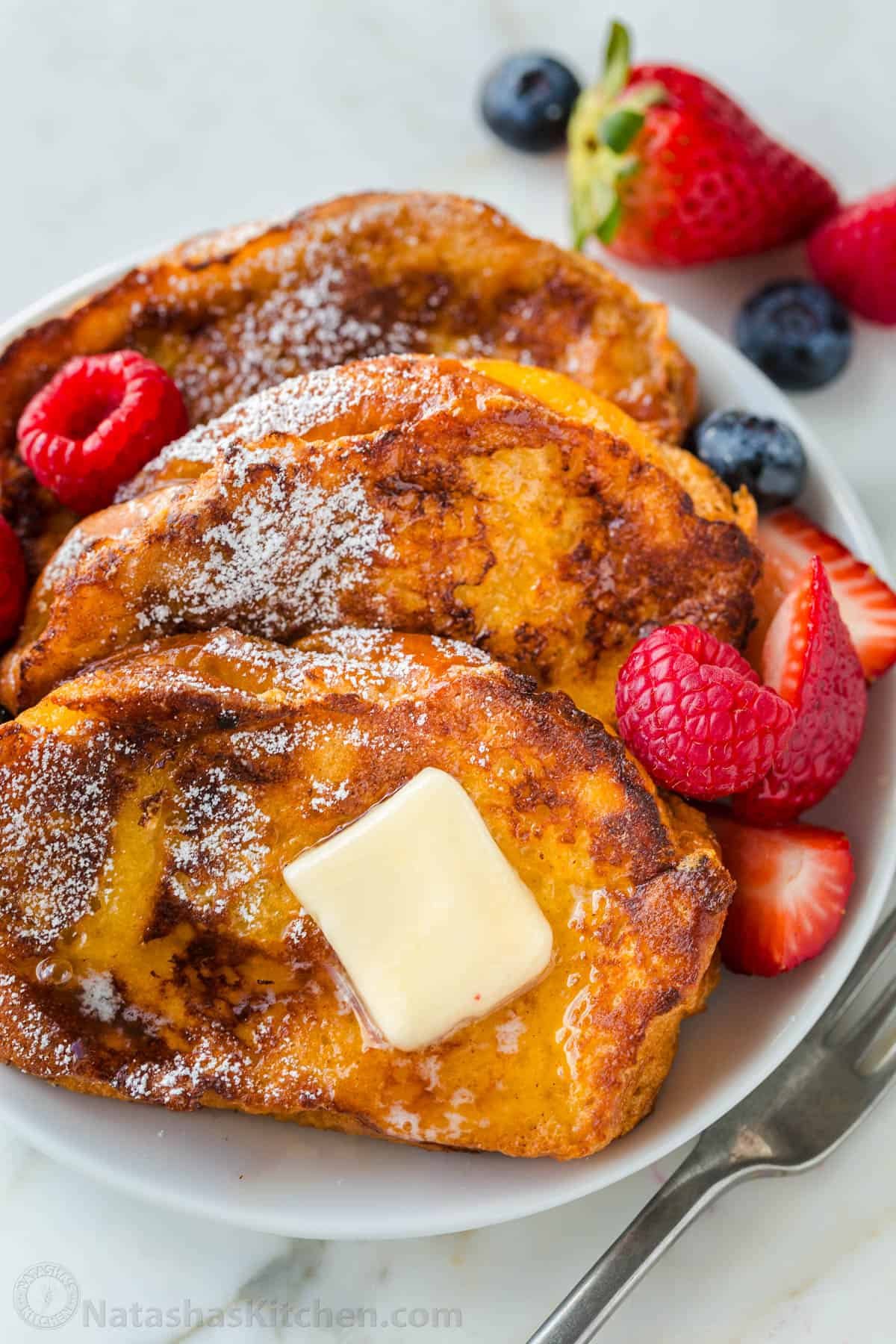 This will be your go-to French Toast Recipe. From the batter to the cooking method, it's easy, excellent, and works with a variety of bread. French Toast on a plate served with butter, powdered sugar and maple syrup