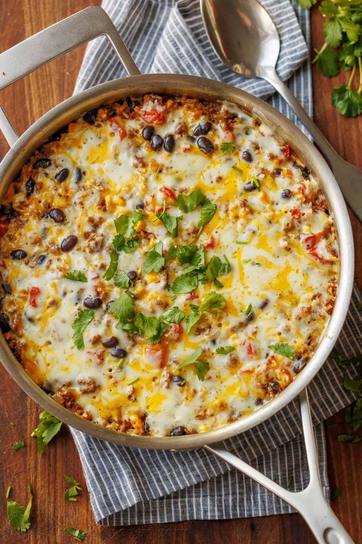 Mexican Beef and Rice Skillet is a quick, 30-minute meal—seasoned beef, loaded rice, and gooey melted cheese. The perfect one-pan wonder! Mexican Beef and Rice skillet prepared and garnished with melted cheese and fresh cilantro