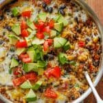 Mexican Beef and Rice Skillet with Serving Spoon and garnished with avocados, tomatoes and cilantro