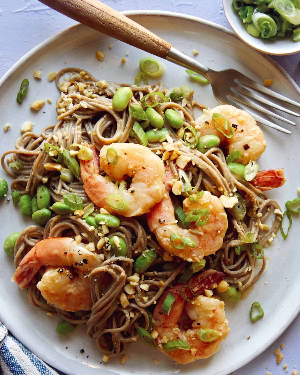 Close up on a soba noodle recipe with shrimp and a fork with it.