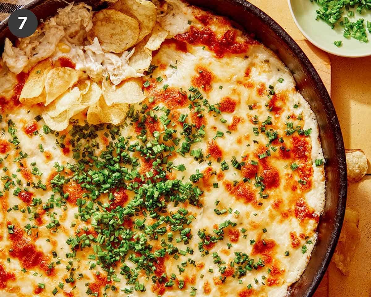 Crab dip recipe in a skillet with potato chips on the side.