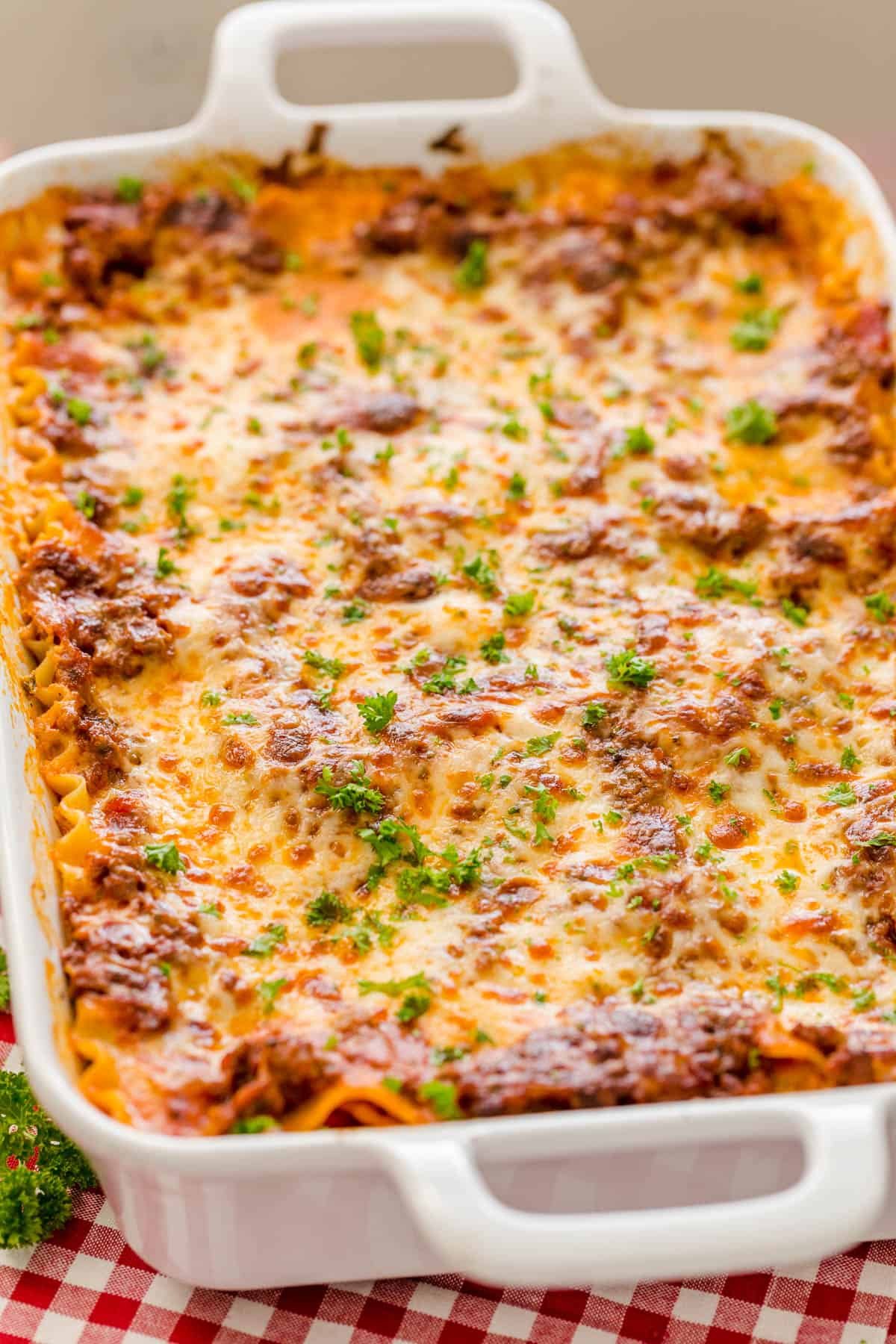 This easy Lasagna Recipe is meaty, cheesy, and flavorful. Perfect for a weeknight dinner or feeding a crowd, readers agree it's the best! Dish of cheesy meat lasagna