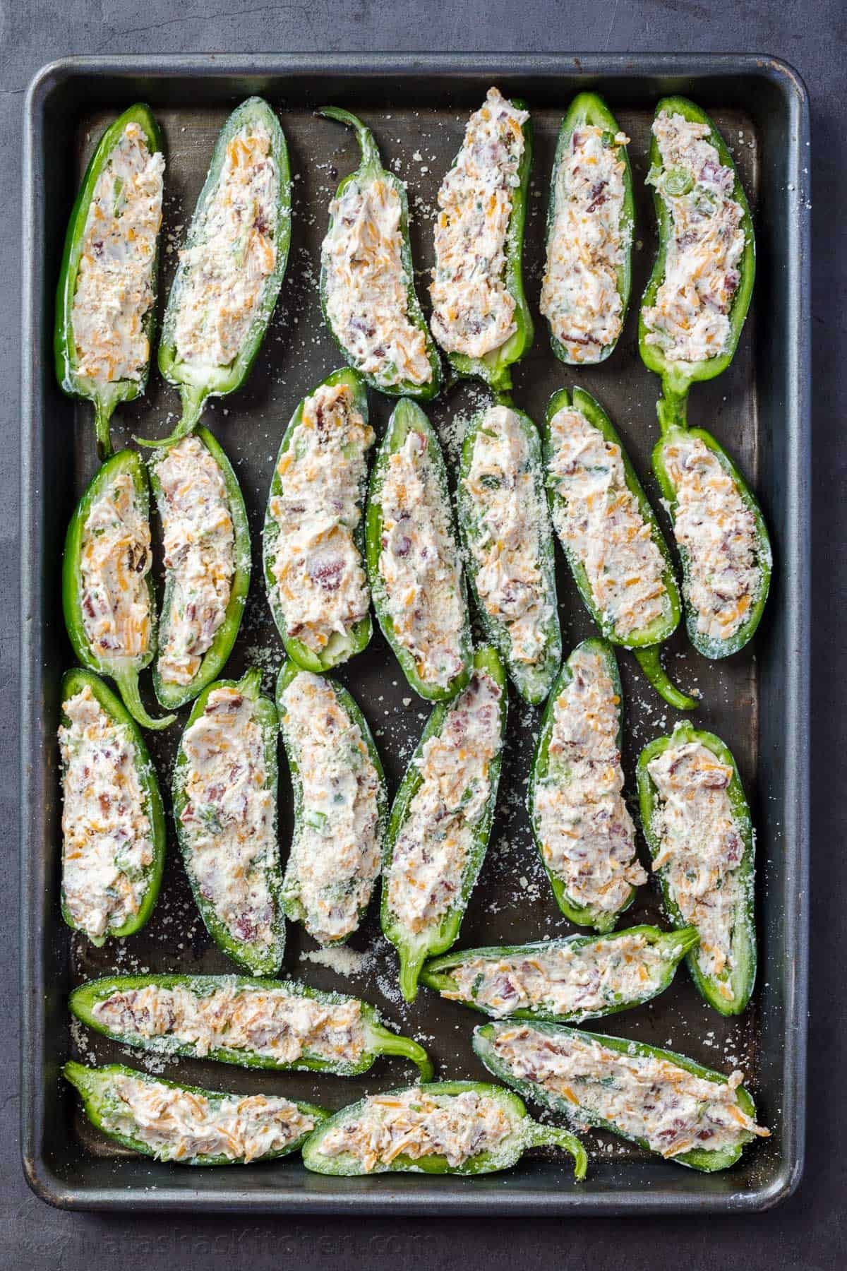 Jalapeno halves stuffed with cream cheese filling, ready to be baked