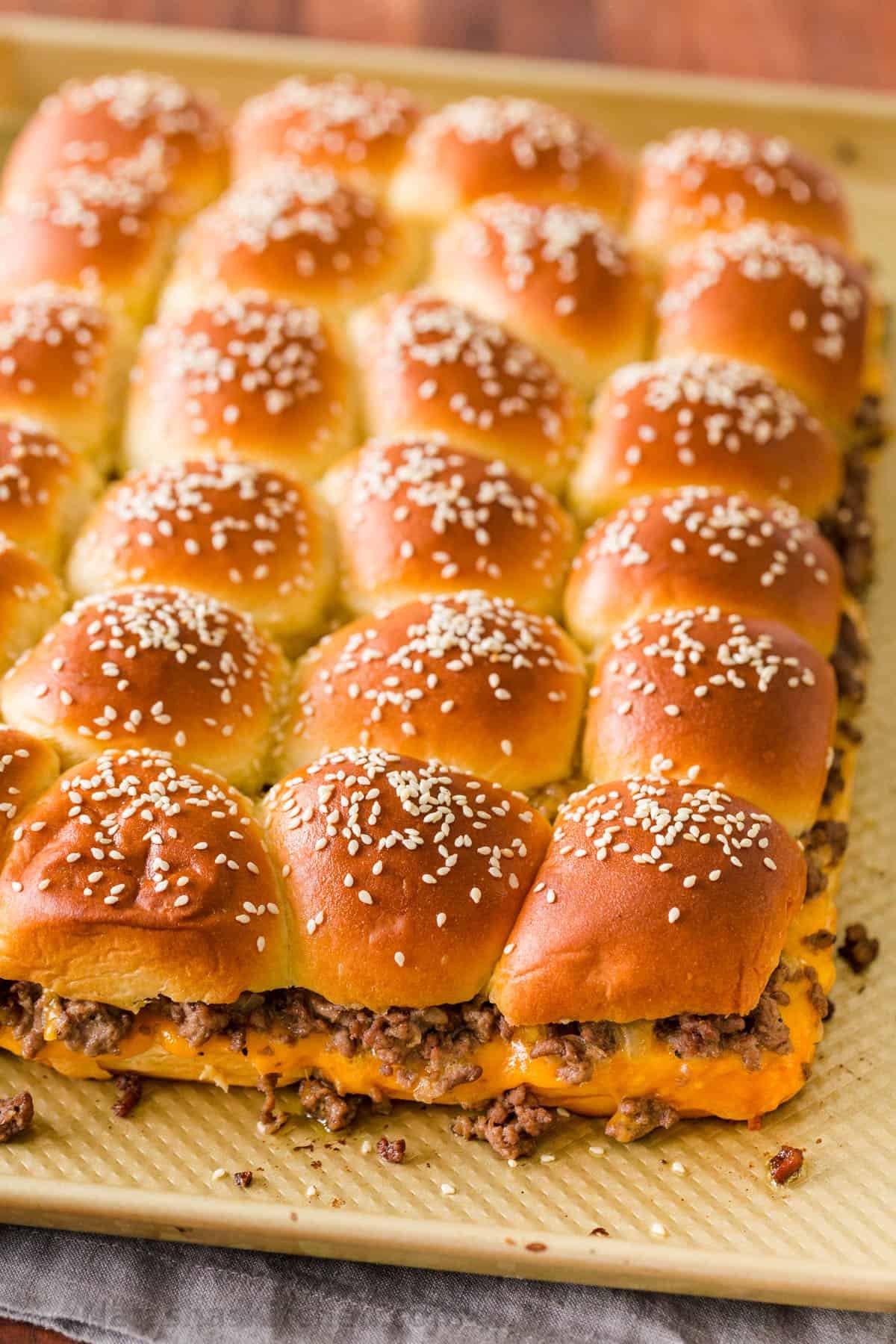 cheeseburger sliders with ground beef Cheeseburger sliders on a baking sheet topped with sesame seeds