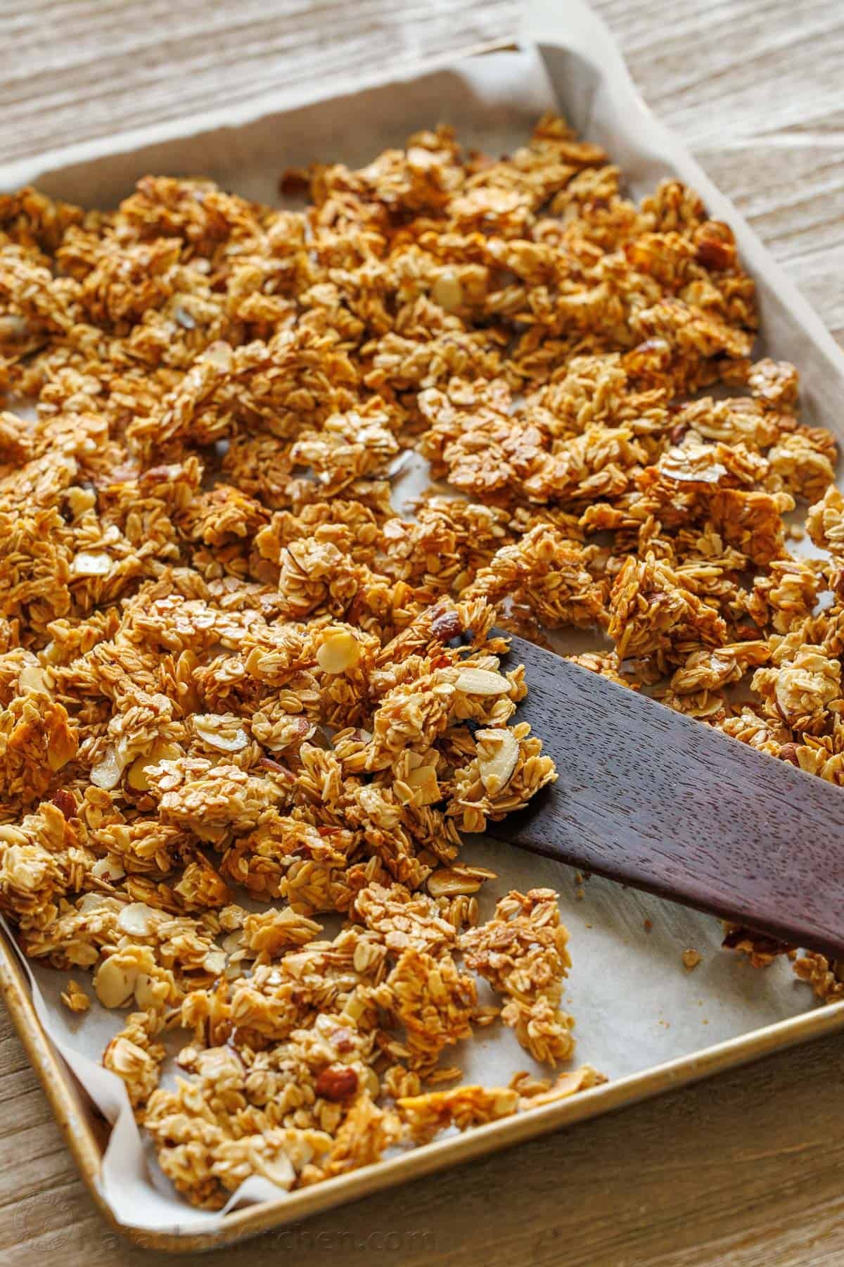 This Homemade Granola Recipe is one of my family's go-to healthy breakfast recipes because it's quick to make and ready to eat all week long. Homemade granola on a baking sheet with a spatula