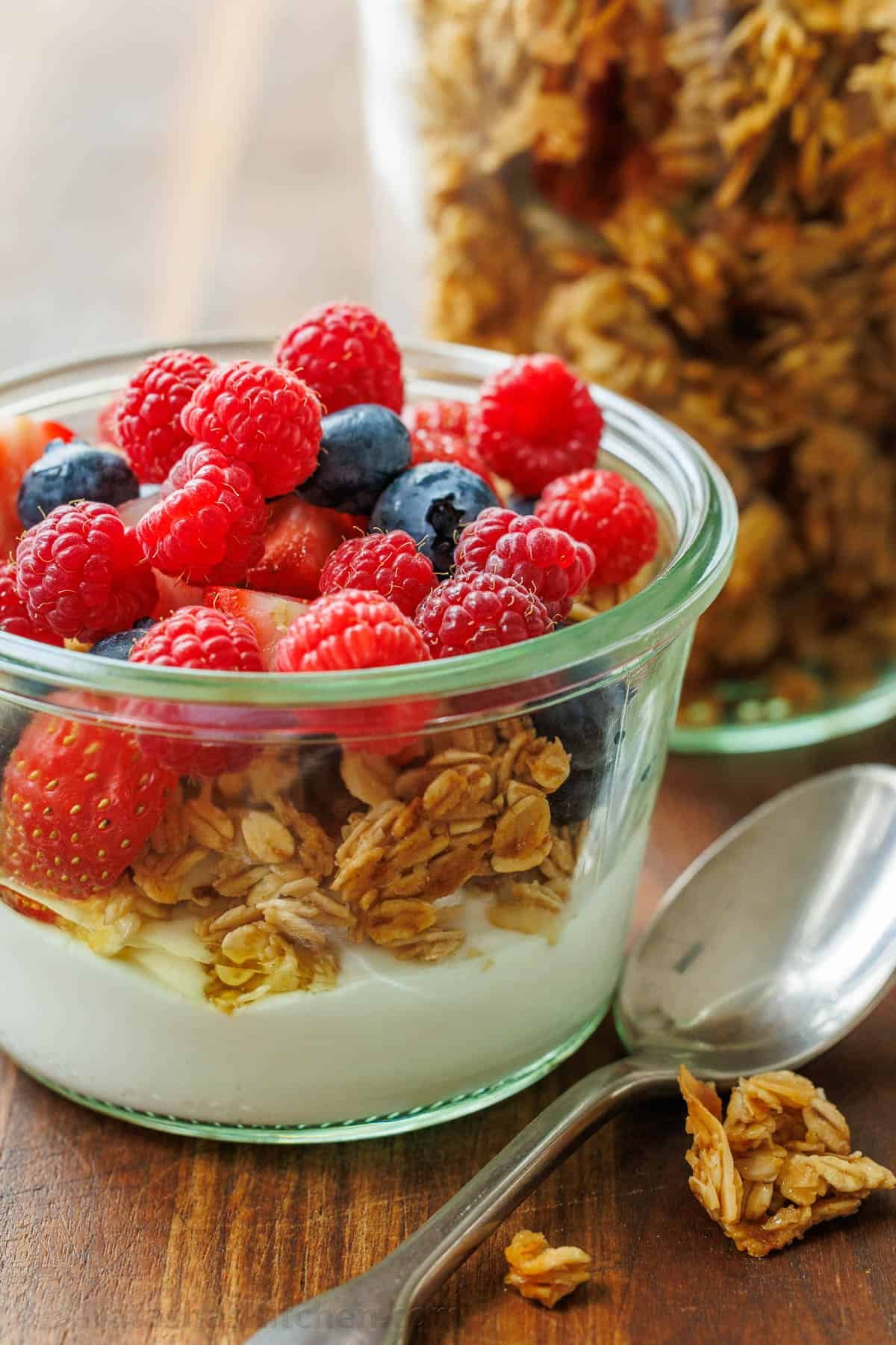 This Homemade Granola Recipe is one of my family's go-to healthy breakfast recipes because it's quick to make and ready to eat all week long. Homemade parfait with homemade granola, Greek yogurt and mixed berries in a glass cup