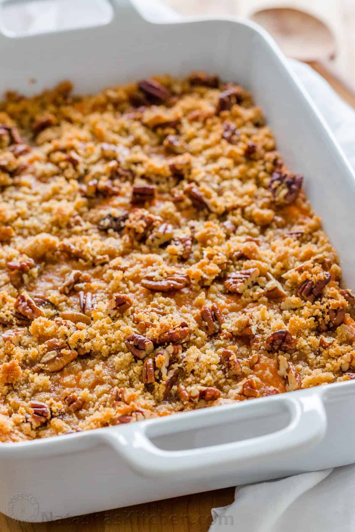 Sweet Potato Casserole with irresistible crunchy pecan topping. This sweet potato bake is smooth and puffs up while baking. A favorite Thanksgiving side! #sweetpotatocasserole #sweetpotatocasserolerecipe #sweetpotato #sweetpotatorecipes #natashaskitchen #thanksgiving #christmas Sweet Potato Casserole in baking casserole dish