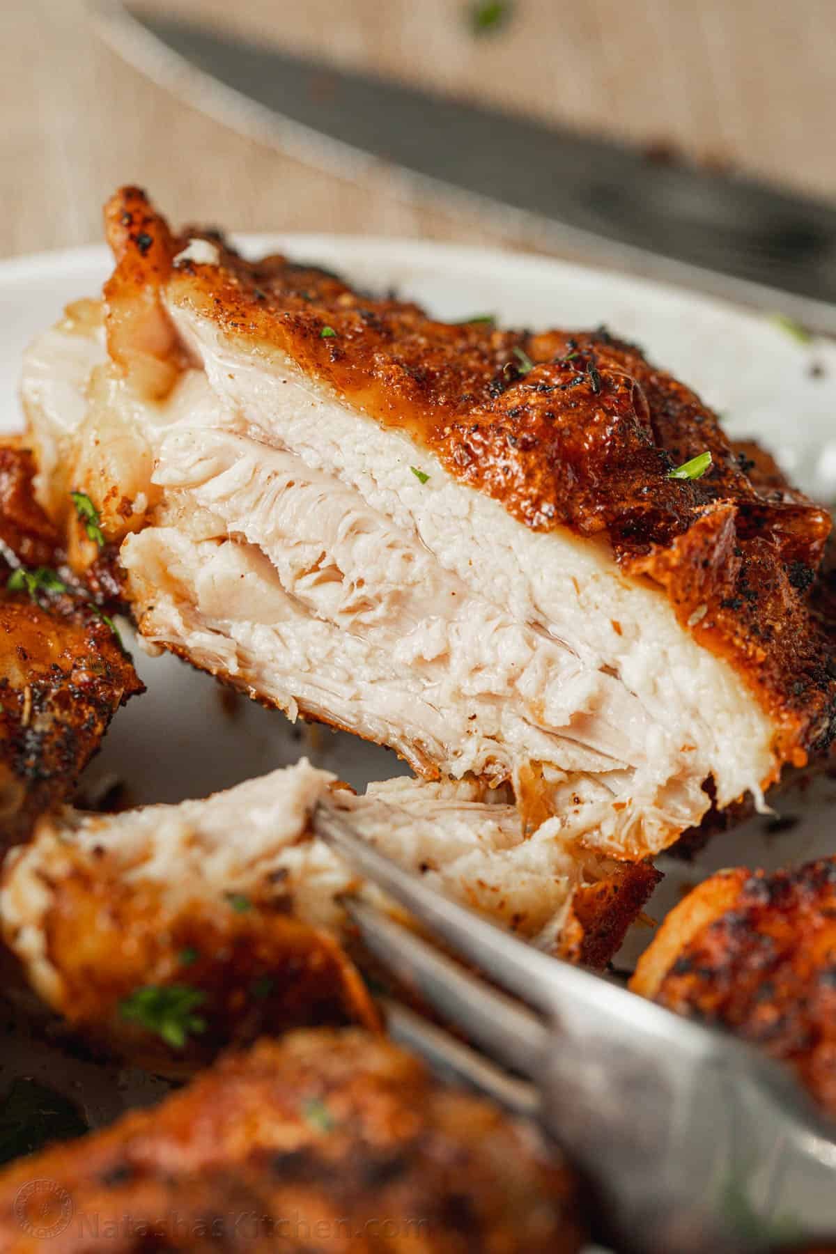 Air Fryer Chicken Thighs are crispy on the outside, so juicy and perfectly seasoned. An air fryer is the fastest way to cook chicken thighs! A forkful of juicy air fried chicken thigh cut away from the the rest of the thigh on a plate.