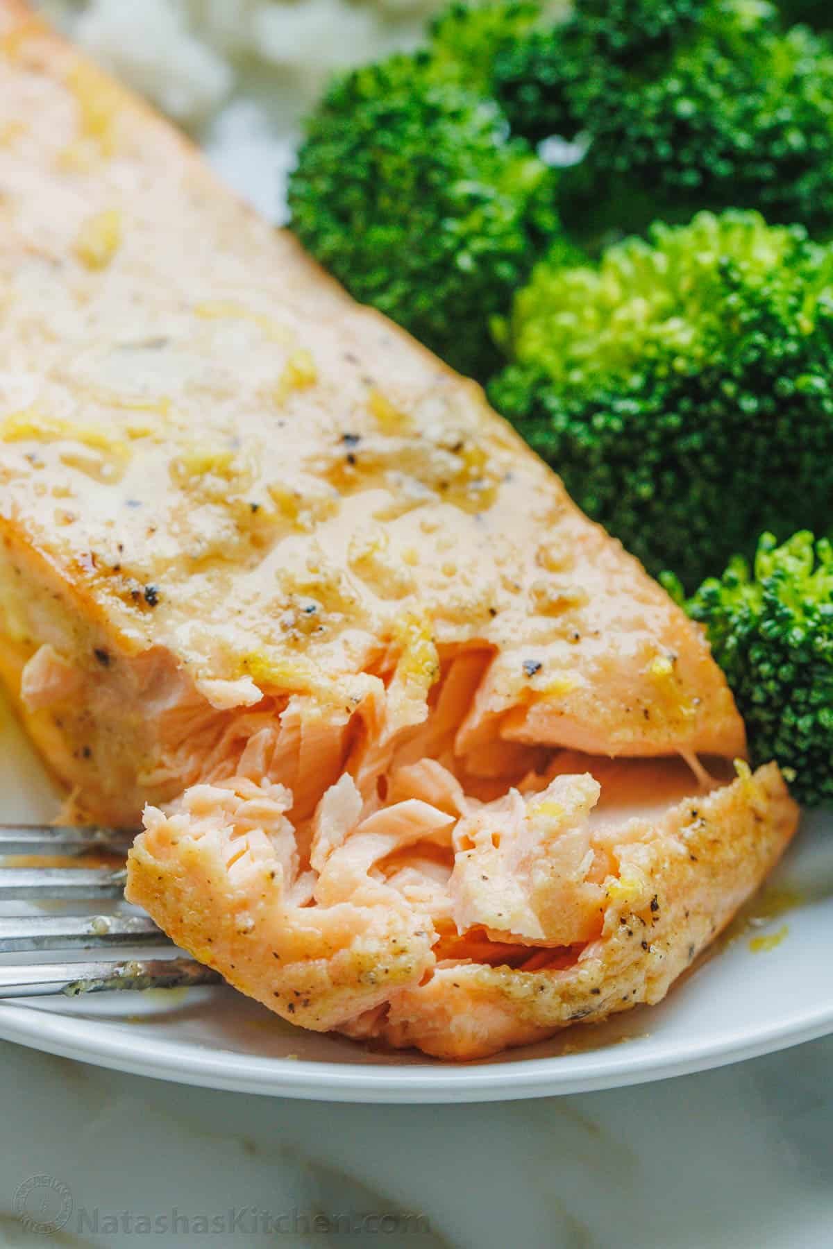 Air Fryer Salmon is one of the best ways to cook salmon in 10 minutes! The air fryer creates a crisp edge with a flaky and juicy center. Air fryer salmon fillet on a white plate served with a side of rice and broccoli.