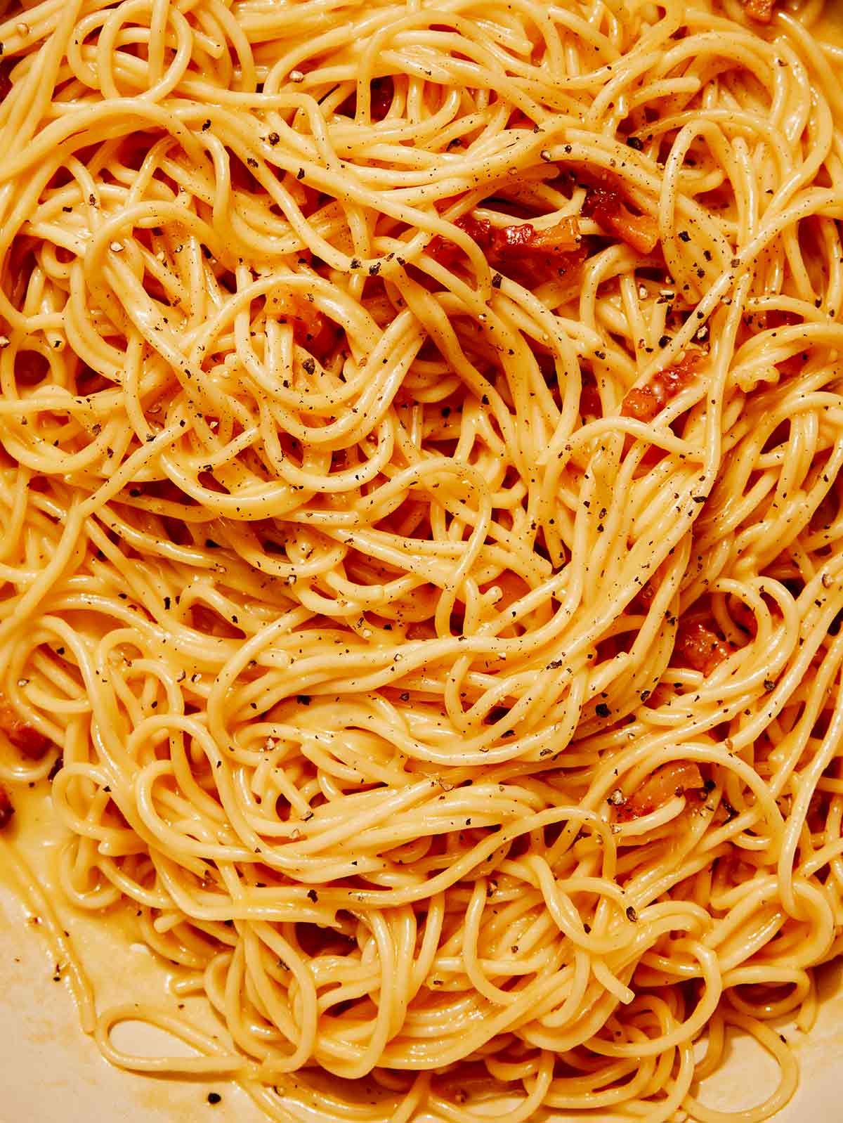 Carbonara in a skillet being tossed.