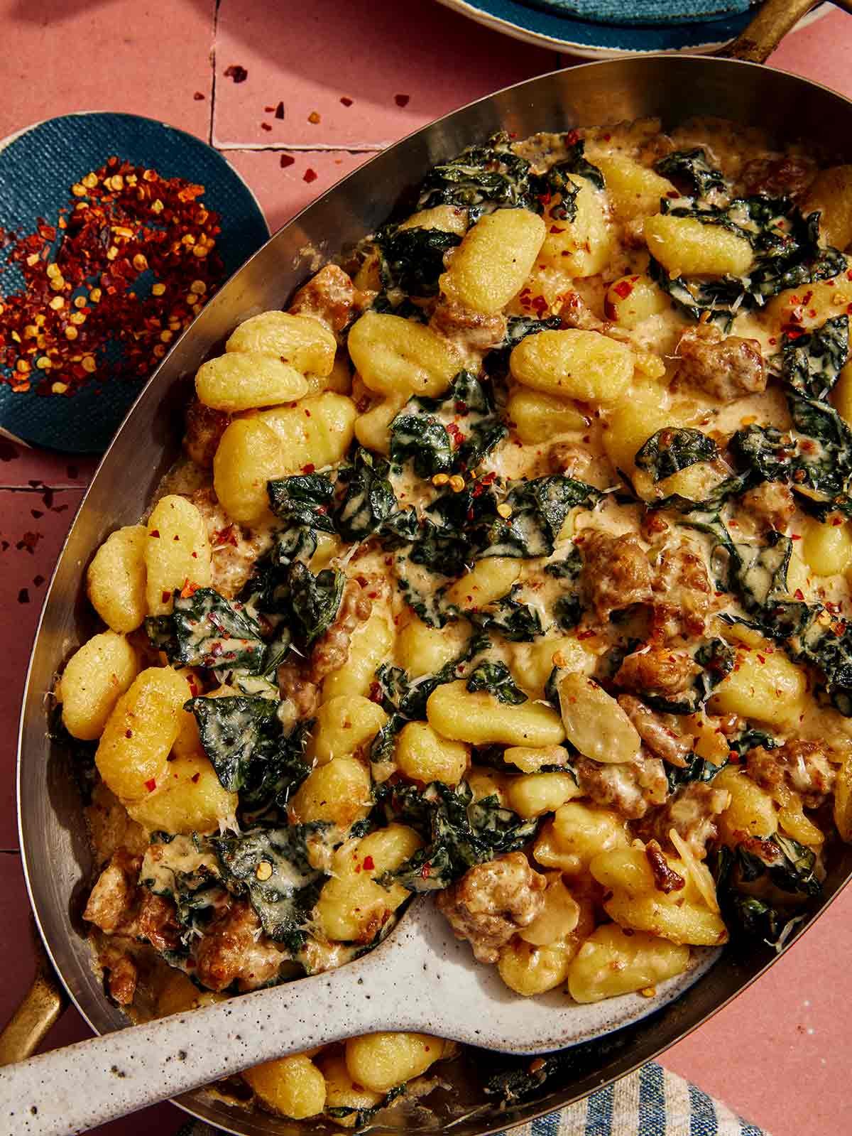 Baked gnocchi with some red pepper flakes on the side.