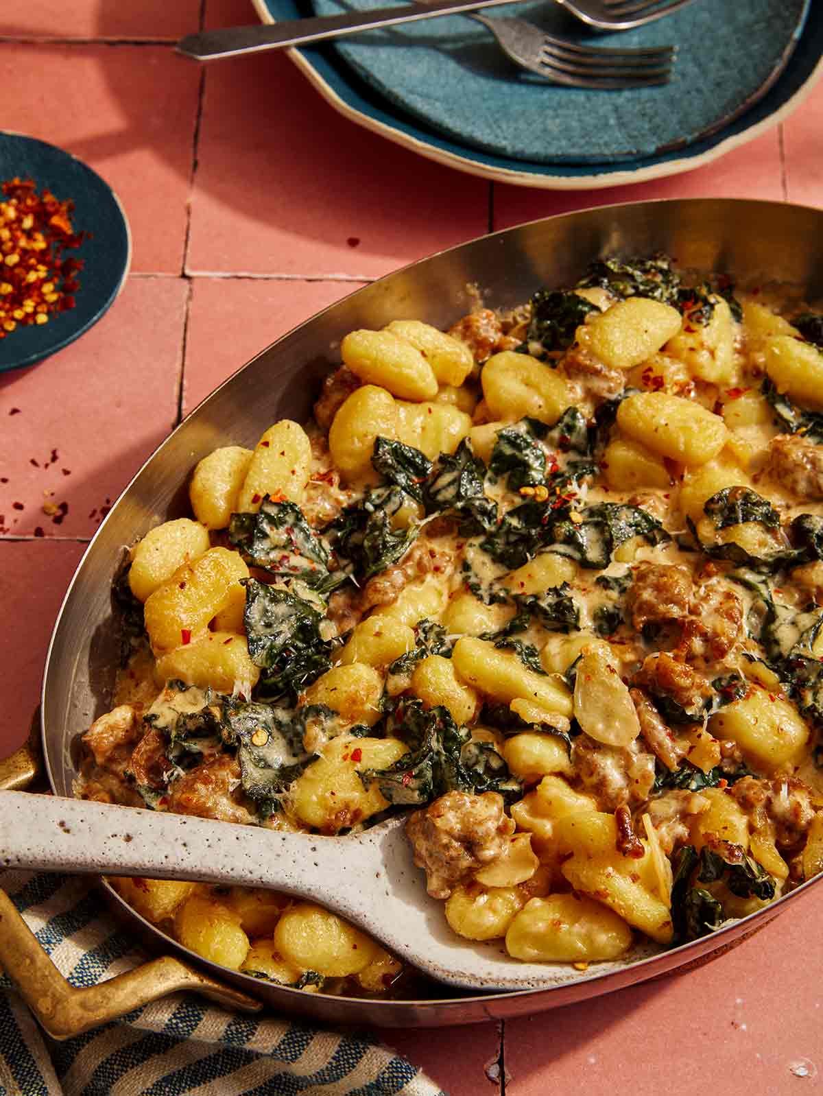 Baked gnocchi in a pan being scooped out to serve.