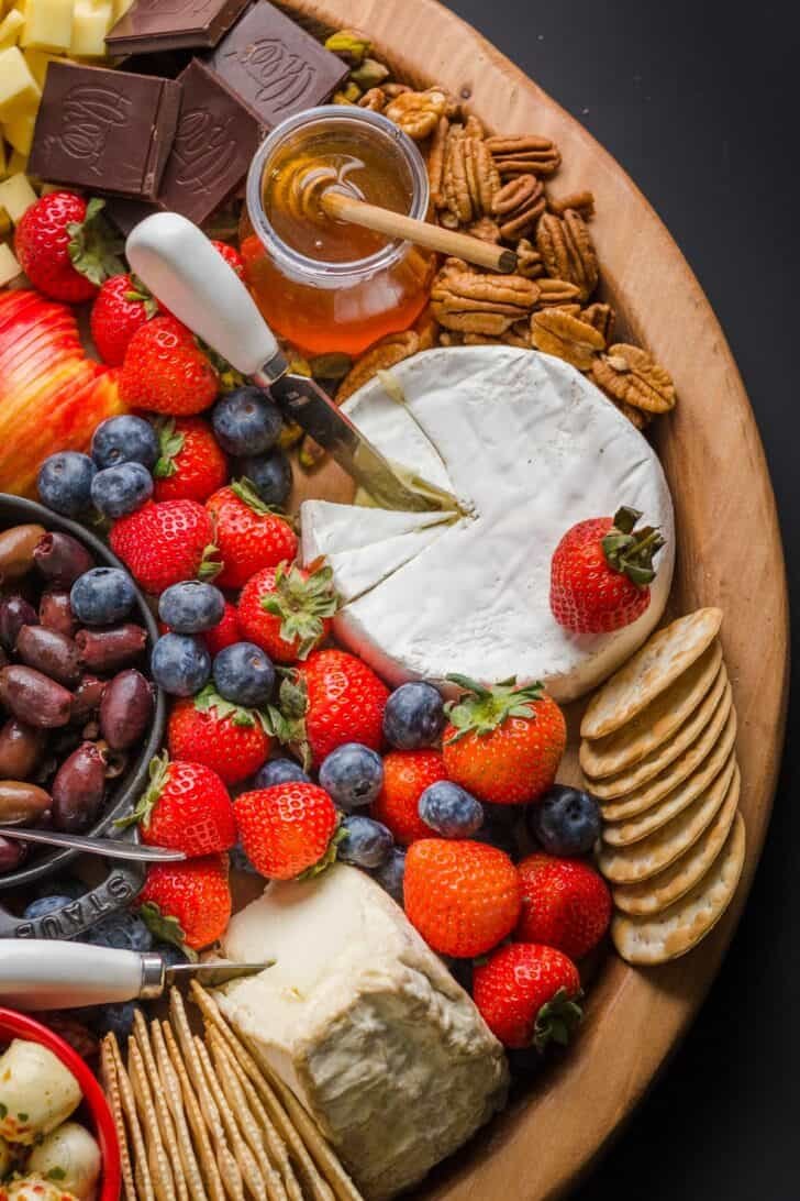 Making a Charcuterie Board is easier than you think. Sharing the best flavor pairings, and tips for arranging a meat and cheese board. Cheese, fruit, nuts, and condiments arranged on a charcuterie board