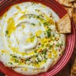 Whipped feta dip in red bowl with pita chips