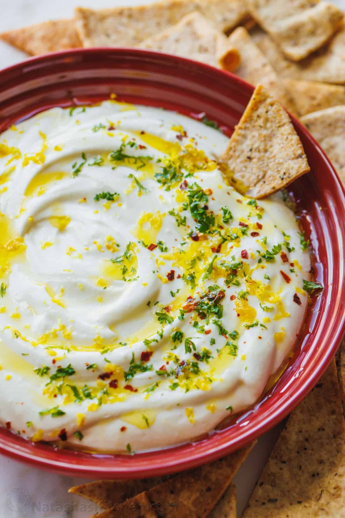 Whipped feta dip in red serving dish with chip