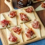 Manchego cheese bites with fig preserves and prosciutto on serving board