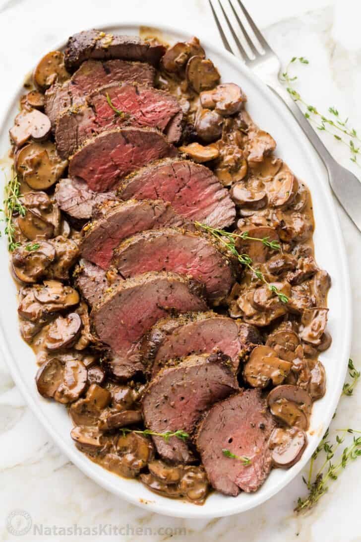 Beef Tenderloin with Mushroom Sauce is a holiday-worthy and impressive main course. Learn how to prep, tie, and cook a beef tenderloin roast in the oven. Platter of filet of beef with mushroom sauce