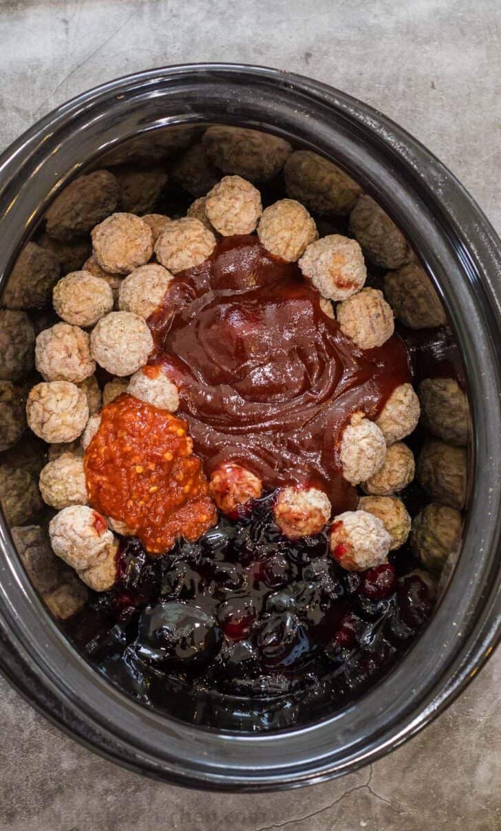 A simple grape jelly meatball recipe that is made using only 4 simple ingredients, the perfect party appetizer for any occasion. A crockpot with frozen meatballs, jam, barbecue, and chili sauce ready to be baked.
