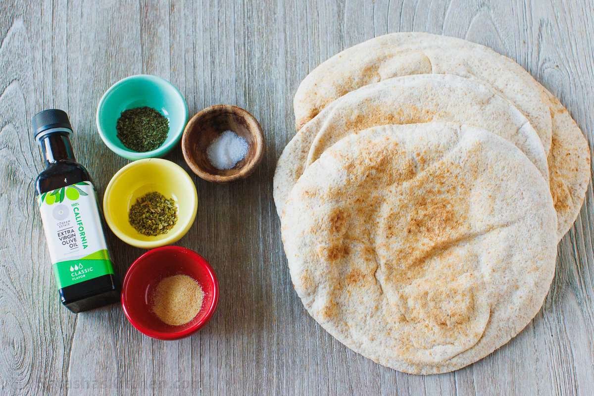 Homemade pita chips are a great way to use leftover pita bread. Crisp, crunchy, perfectly seasoned and more satisfying than store-bought. Ingredients for homemade pita chips with pita bread, seasonings and olive oil