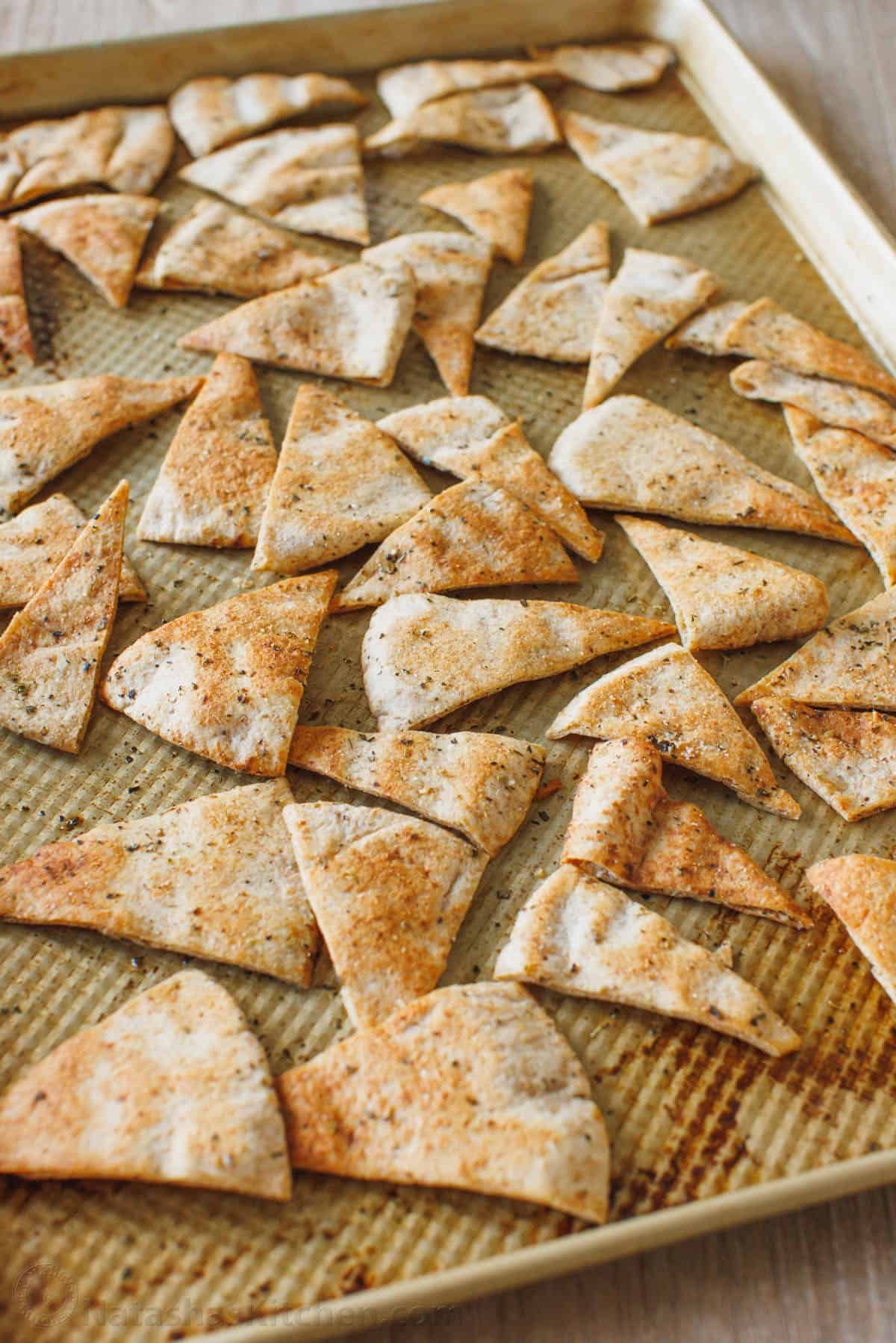 Homemade pita chips are a great way to use leftover pita bread. Crisp, crunchy, perfectly seasoned and more satisfying than store-bought. Pita chips seasoned and baked on a baking sheet