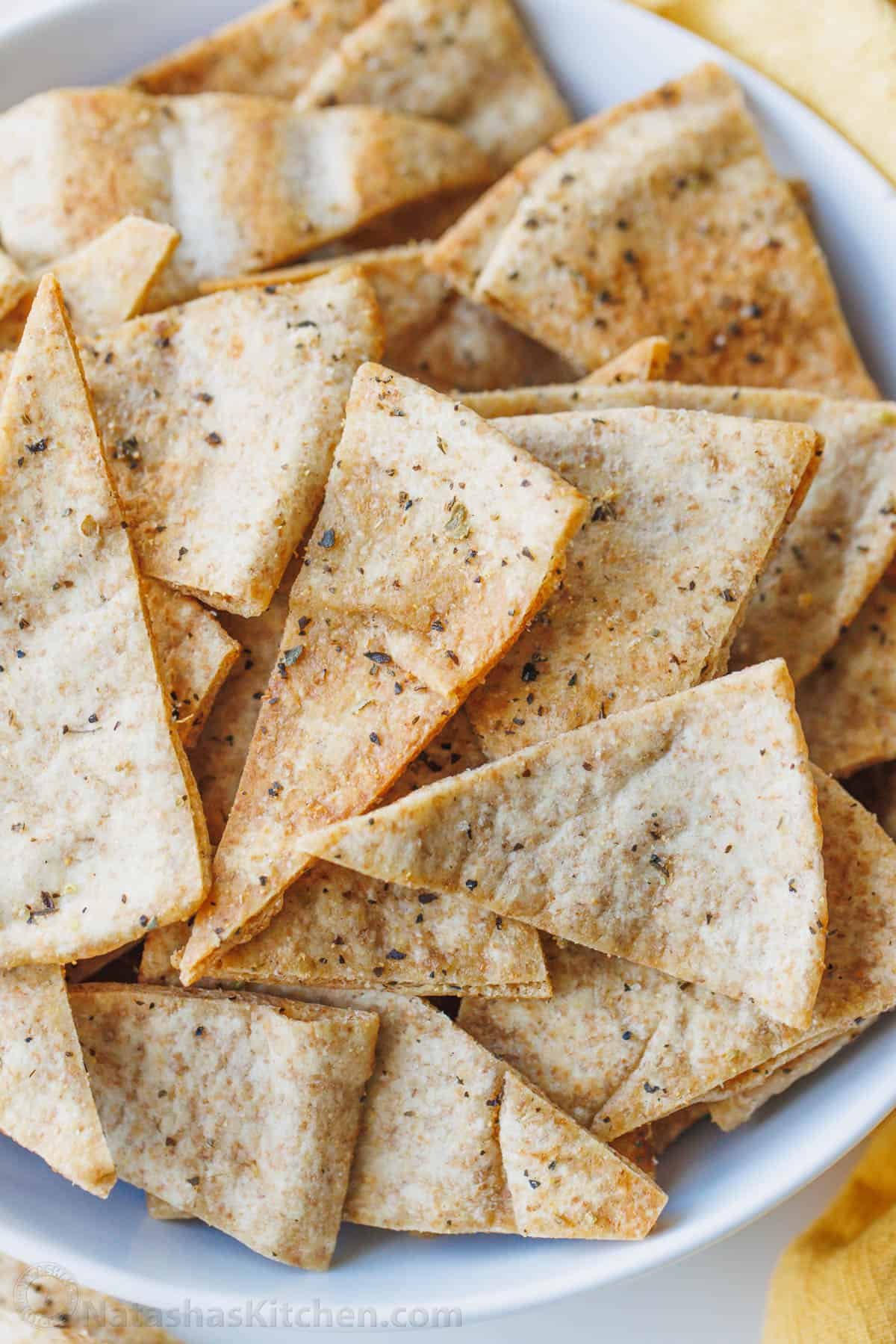 Homemade pita chips are a great way to use leftover pita bread. Crisp, crunchy, perfectly seasoned and more satisfying than store-bought. Baked pita chips cooled and ready to store