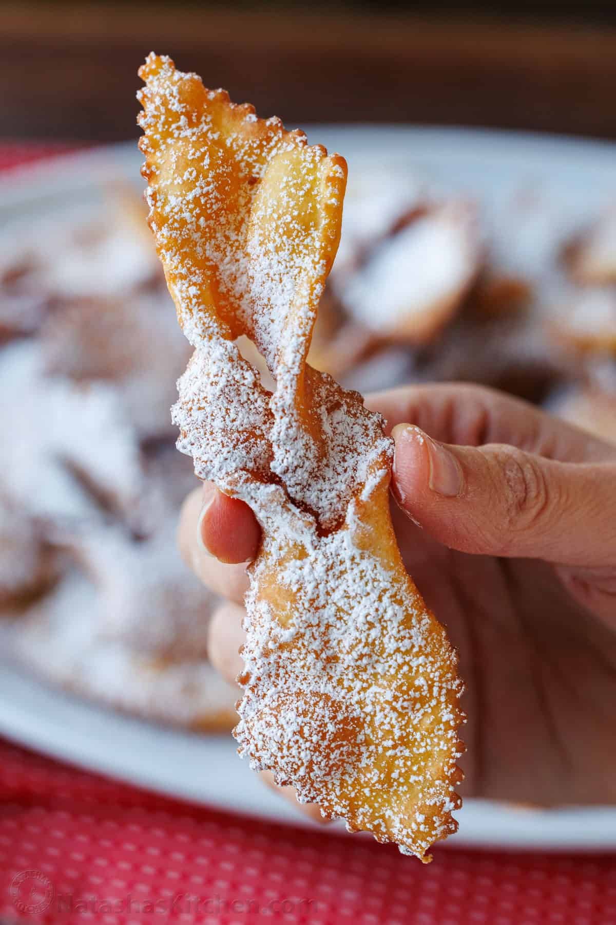 Traditional Angel Wing Cookies (Polish Chrusciki) make a beautiful holiday cookie. These ribbon cookies are dusted with sugar & irresistible. Photo of a folded Angel Wing Cookies