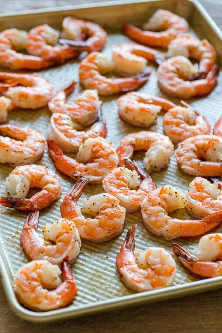 Homemade Shrimp Cocktail is impressive and easy with the best oven-baked shrimp and zesty shrimp cocktail sauce. Way better than a store-bought shrimp ring! #shrimpcocktail #shrimpcocktailrecipe #shrimpcocktailsauce #cocktailsauce #homemadecocktailsauce #condiments #dip #shrimp #appetizer #shrimpappetizer How to bake shrimp on a baking sheet in the oven