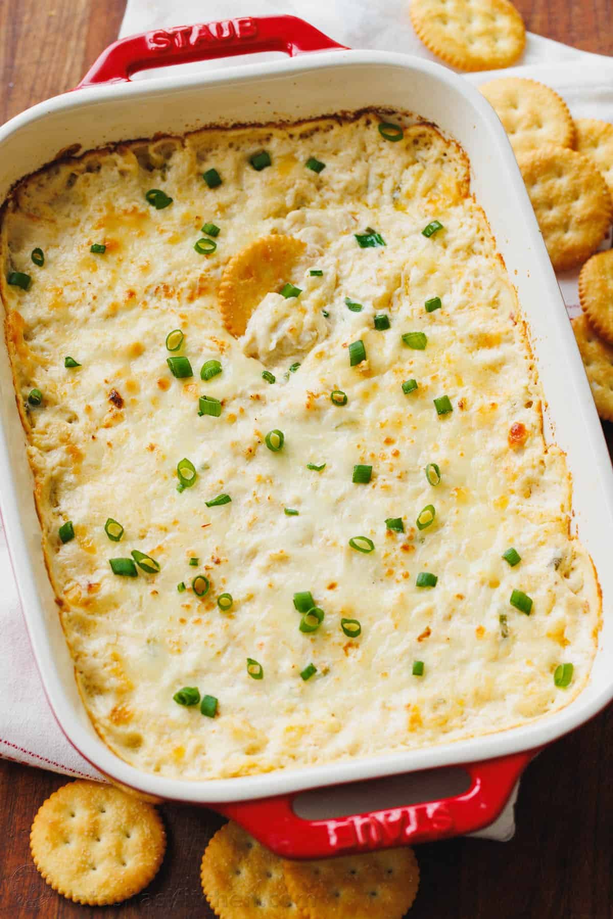Creamy and cheesy hot Crab Dip is irresistibly good. It's loaded with lump crab meat and will be the star appetizer of your holiday menu. Casserole of hot crab dip garnished with chives