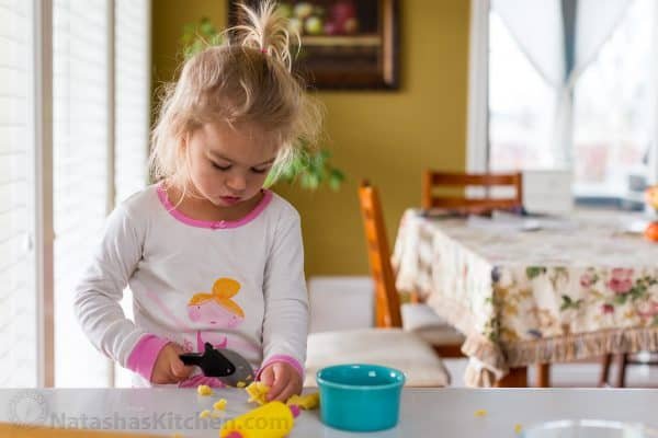 A little girl sitting at a table playing with play dough