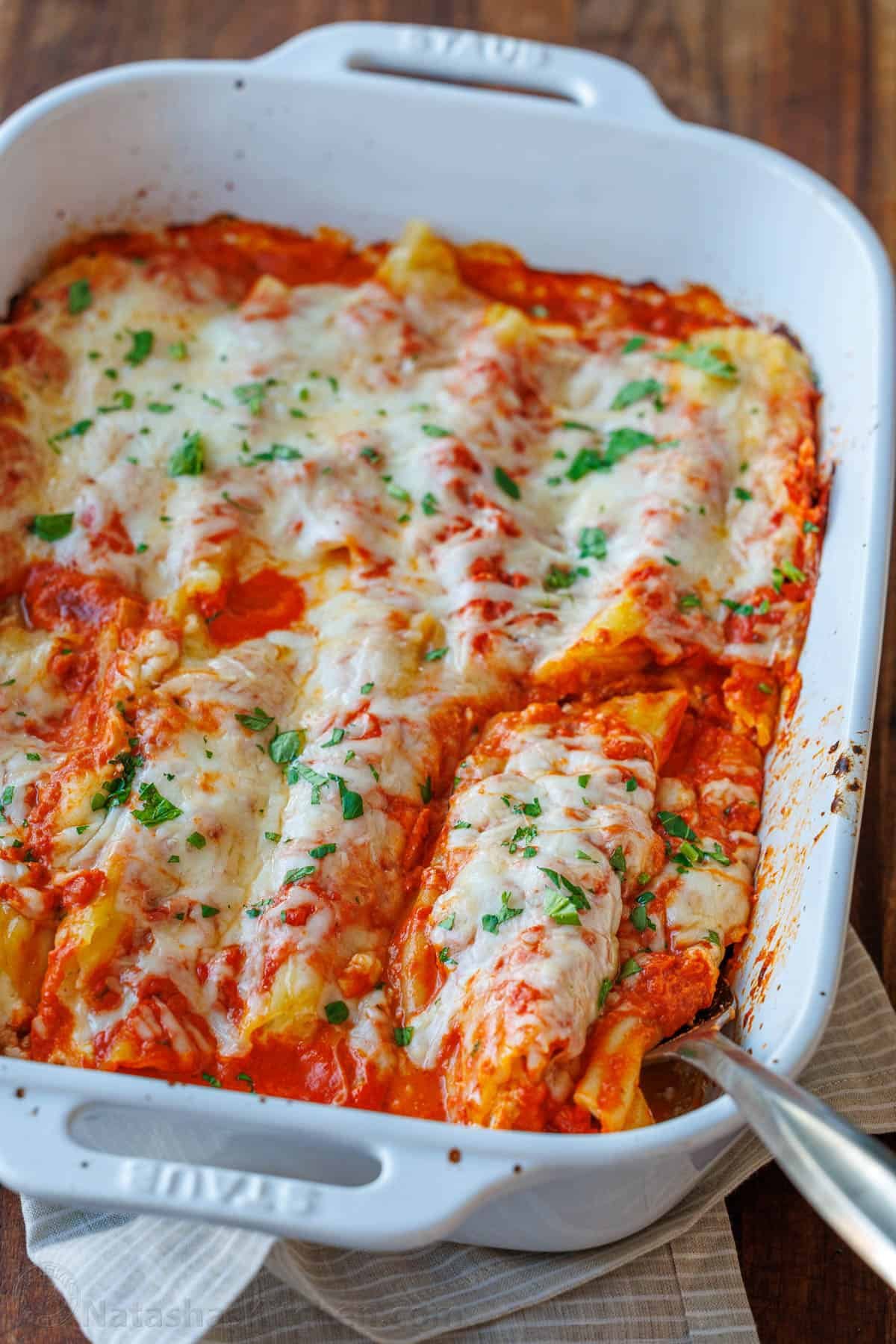 Our Stuffed Manicotti recipe has three kinds of cheese stuffed into perfectly cooked pasta, smothered in marinara sauce, and baked perfectly. Learn how to make the best stuffed manicotti! Baked Cheese manicotti recipe in a dish with parsley