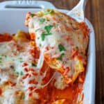 Serving stuffed Manicotti with melted cheese in a white dish